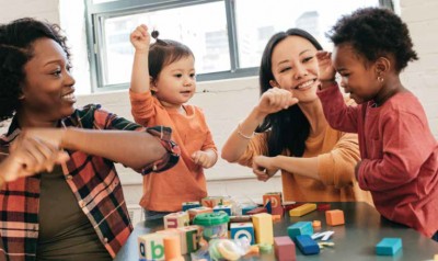 Two adults at a table playing with two toddlers.